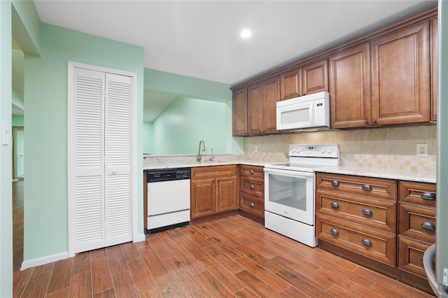 kitchen featuring white appliances, tasteful backsplash, dark wood-type flooring, sink, and light stone counters