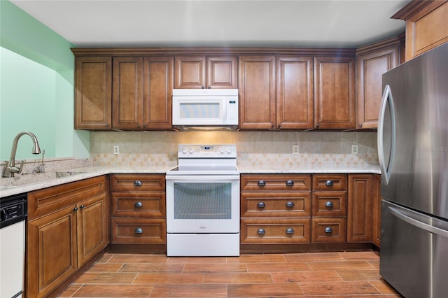 kitchen with sink, light stone countertops, white appliances, and decorative backsplash