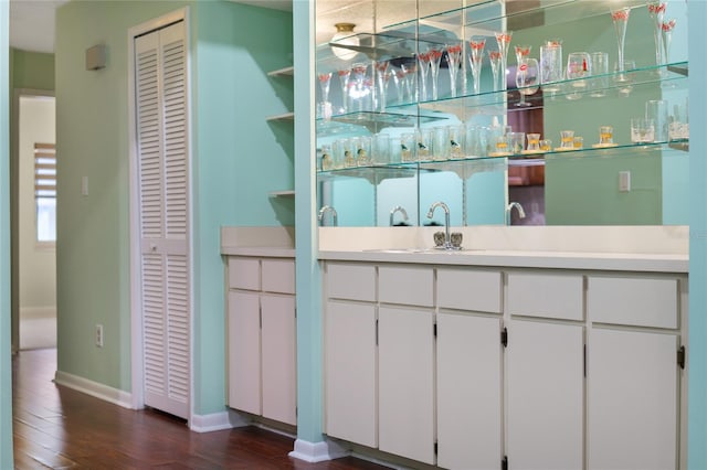 bar with hardwood / wood-style flooring, white cabinetry, and sink