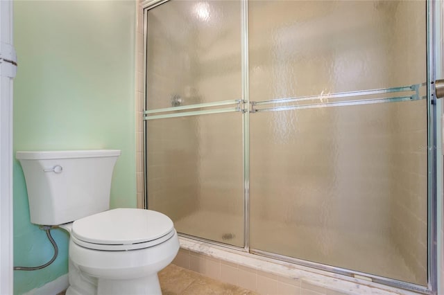 bathroom with toilet, a shower with shower door, and tile patterned flooring