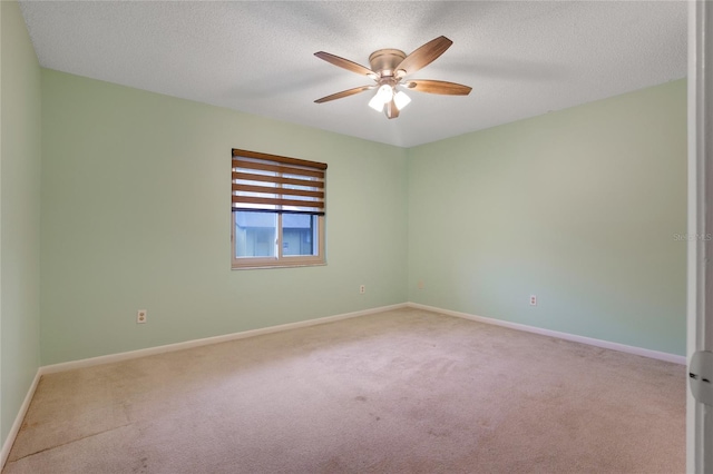 spare room with light colored carpet, ceiling fan, and a textured ceiling