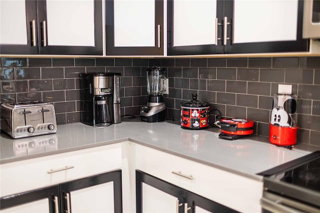 kitchen with white cabinets, decorative backsplash, and range