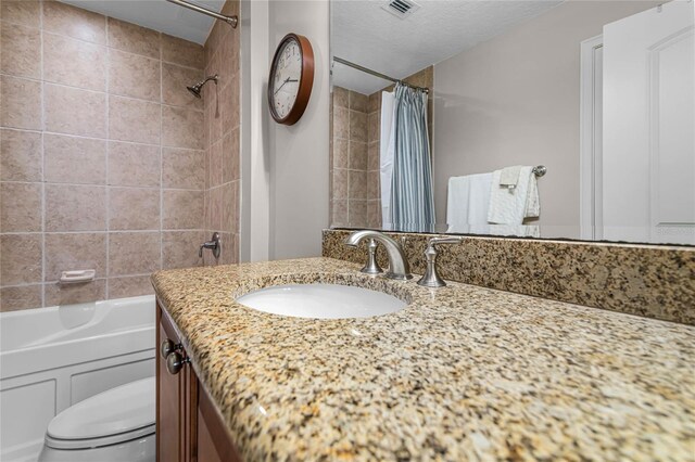 full bathroom featuring vanity, a textured ceiling, shower / bath combination with curtain, and toilet