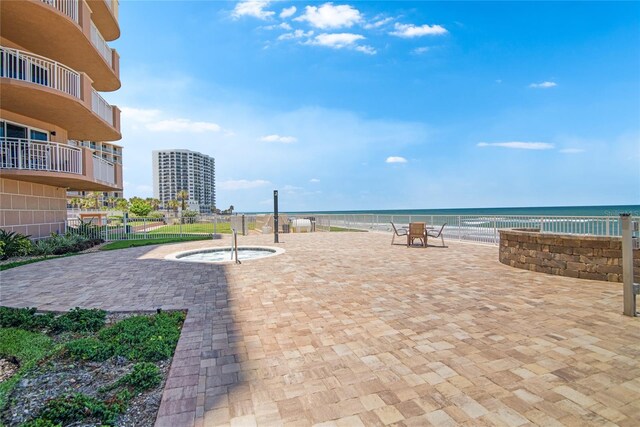 view of community featuring a patio, a water view, and a beach view