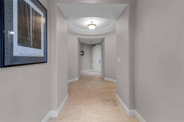 hallway featuring light tile patterned floors and a tray ceiling