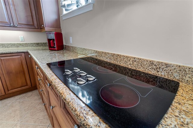 interior space with light stone counters, black electric stovetop, and light tile patterned floors