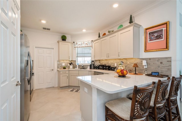 kitchen featuring a kitchen breakfast bar, kitchen peninsula, stainless steel refrigerator with ice dispenser, and ornamental molding