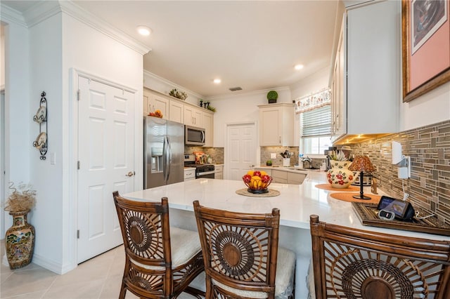 kitchen with kitchen peninsula, appliances with stainless steel finishes, tasteful backsplash, sink, and light tile patterned floors