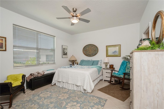 tiled bedroom with ceiling fan and a textured ceiling