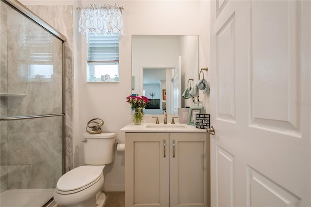 bathroom with vanity, toilet, and a shower with door