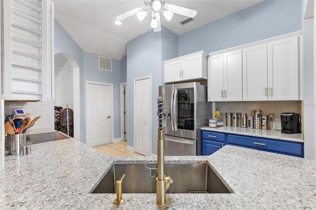 kitchen with white cabinets, stainless steel fridge, blue cabinetry, and tasteful backsplash