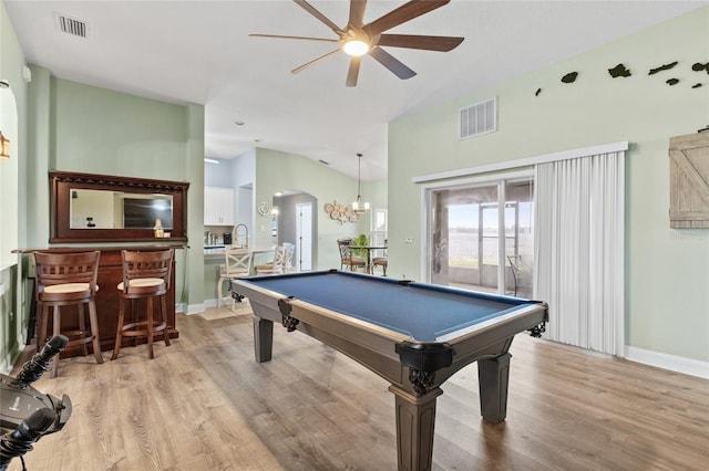 playroom featuring bar area, ceiling fan with notable chandelier, billiards, vaulted ceiling, and light hardwood / wood-style flooring