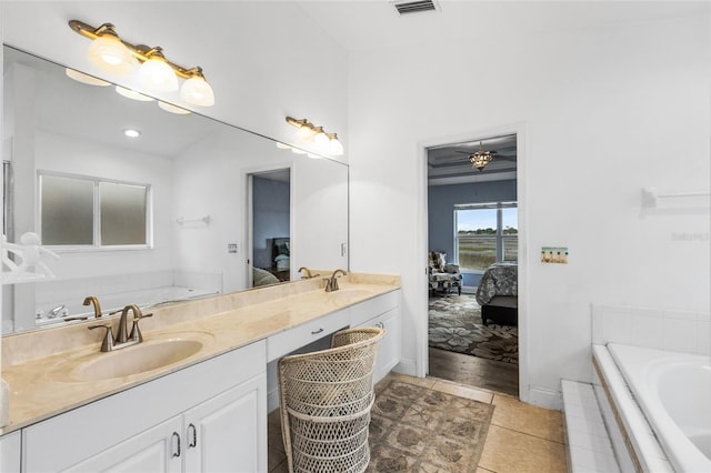 bathroom with tiled tub, tile patterned flooring, and vanity