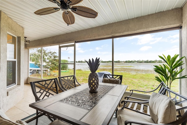 sunroom with ceiling fan and a water view