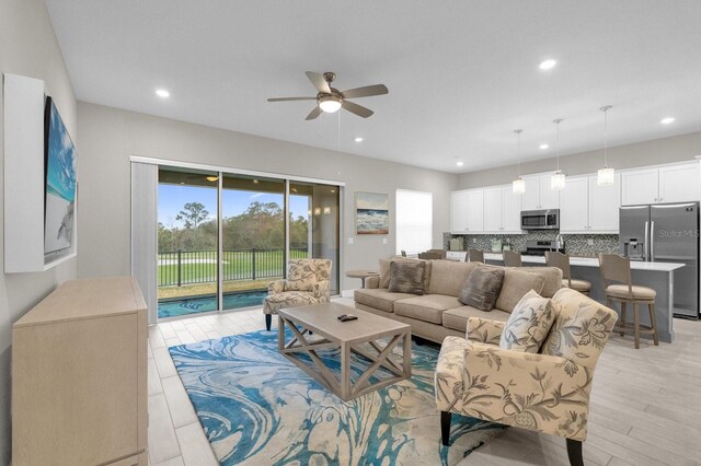 living area with light wood-type flooring, ceiling fan, and recessed lighting