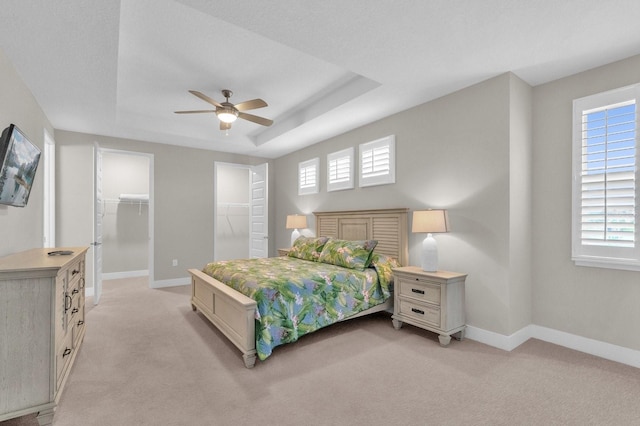 bedroom with baseboards, multiple windows, and a tray ceiling