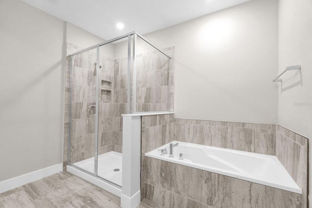 bathroom featuring a stall shower, baseboards, and a garden tub