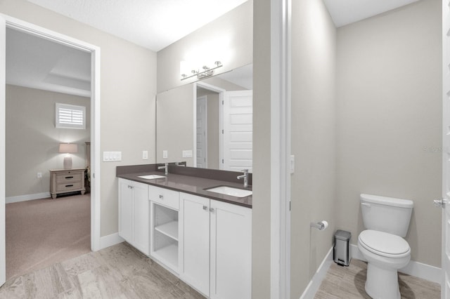 bathroom featuring double vanity, a sink, toilet, and baseboards