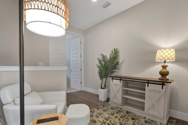 living area with visible vents, baseboards, and wood finished floors