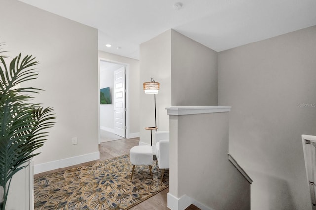 interior space with recessed lighting, wood finished floors, an upstairs landing, and baseboards