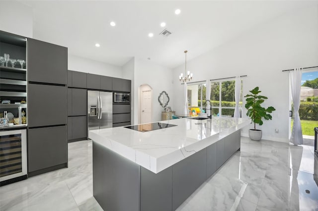 kitchen with hanging light fixtures, beverage cooler, built in appliances, and a large island