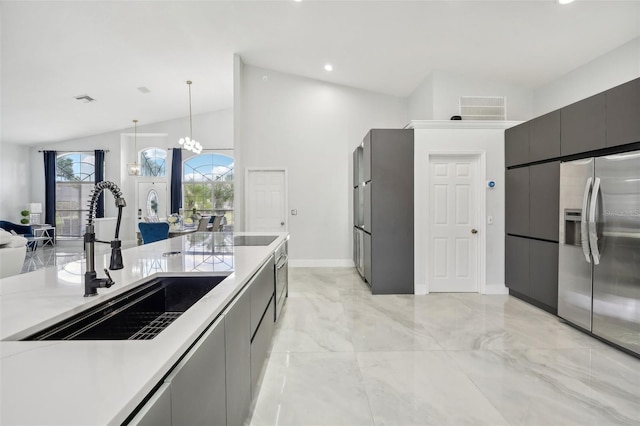 kitchen with stainless steel refrigerator with ice dispenser, sink, hanging light fixtures, a chandelier, and vaulted ceiling