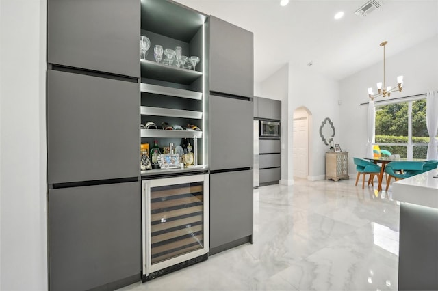 interior space with appliances with stainless steel finishes, pendant lighting, beverage cooler, and gray cabinets