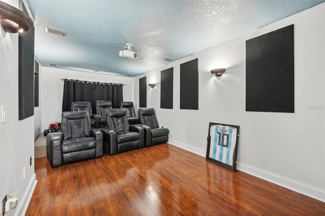 cinema room featuring a textured ceiling and hardwood / wood-style flooring