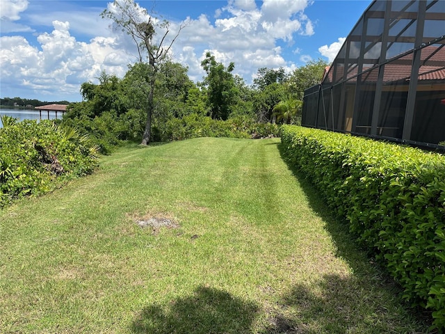 view of yard featuring glass enclosure and a water view