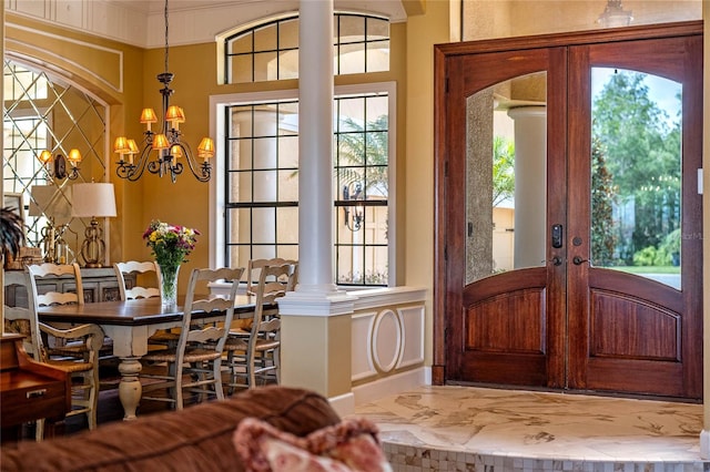 entryway featuring ornate columns, a chandelier, french doors, and a healthy amount of sunlight