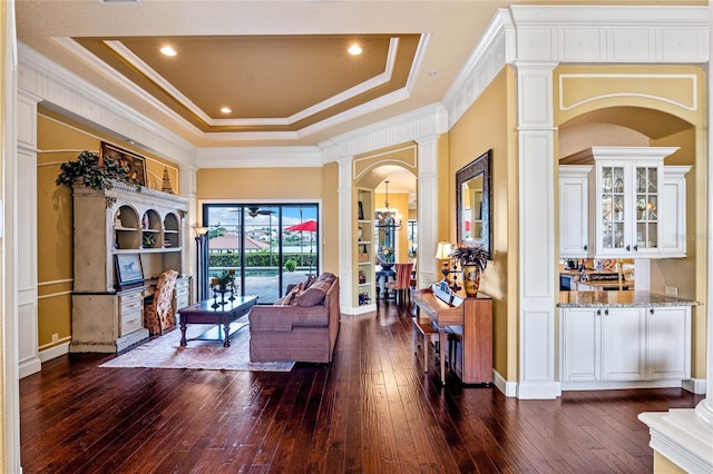 sitting room with dark hardwood / wood-style flooring, decorative columns, and a tray ceiling