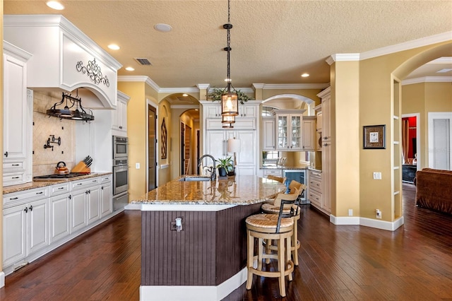 kitchen with sink, dark hardwood / wood-style flooring, white cabinetry, and an island with sink