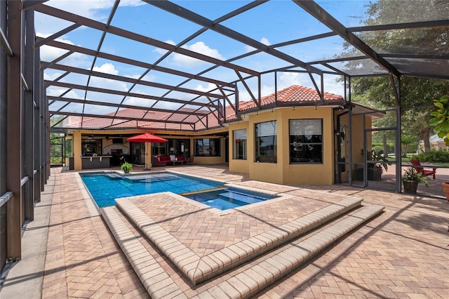 view of swimming pool with glass enclosure, an in ground hot tub, and a patio area