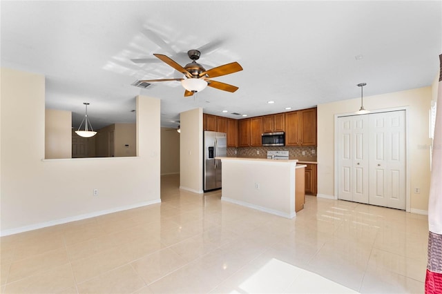 kitchen with stainless steel appliances, a kitchen island, tasteful backsplash, decorative light fixtures, and light tile patterned floors