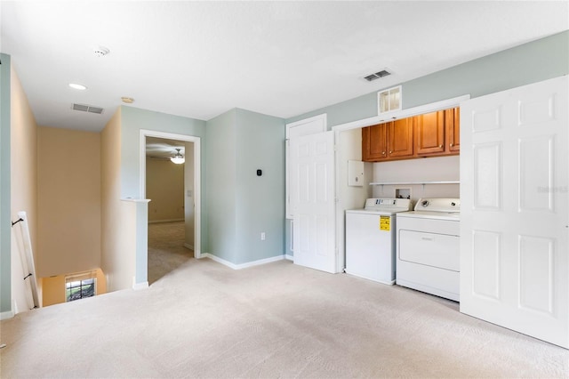 laundry room featuring light carpet, washer and dryer, and cabinets