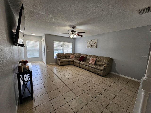 tiled living room with ceiling fan and a textured ceiling