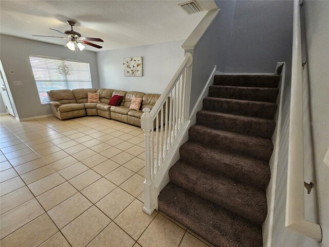 stairs with a textured ceiling, ceiling fan, and light tile floors