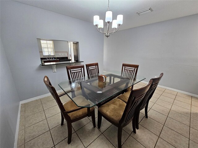 tiled dining area featuring a notable chandelier and sink