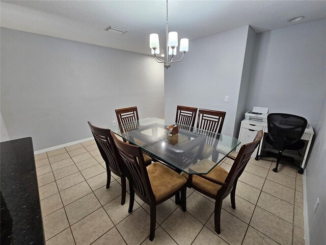 tiled dining area with a chandelier and a textured ceiling