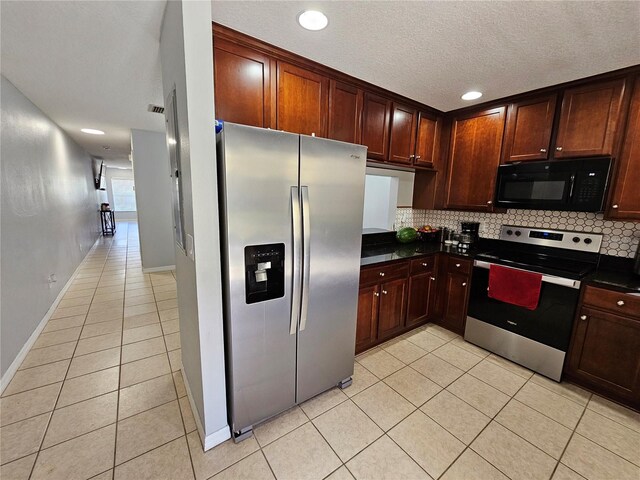 kitchen with stainless steel appliances, light tile floors, a textured ceiling, and backsplash