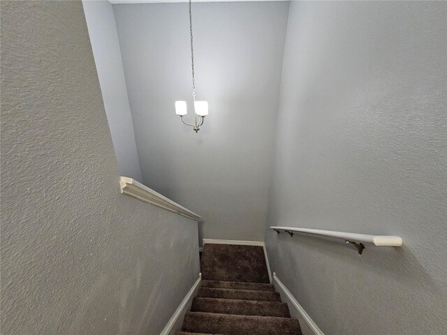 stairway featuring dark colored carpet