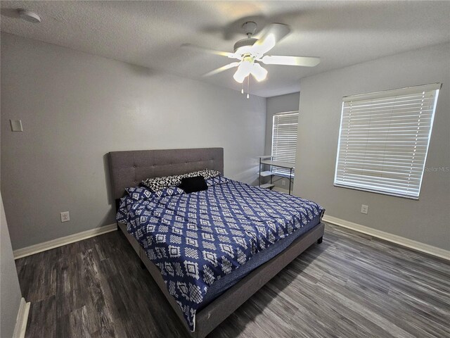 bedroom with dark hardwood / wood-style flooring, ceiling fan, and a textured ceiling