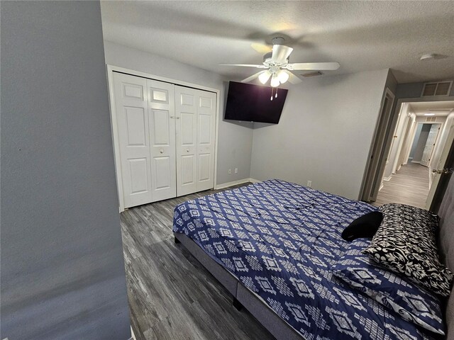 bedroom featuring dark hardwood / wood-style floors, ceiling fan, a closet, and a textured ceiling