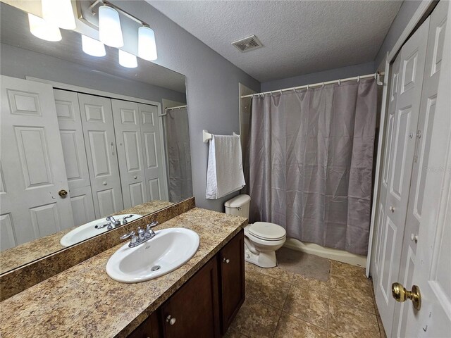 bathroom with tile flooring, a textured ceiling, toilet, and vanity