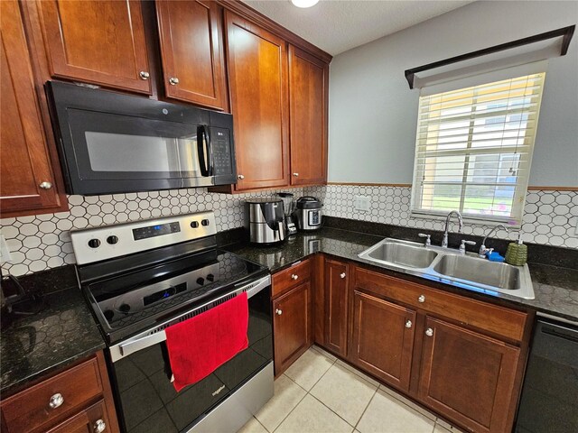 kitchen with light tile flooring, tasteful backsplash, black appliances, dark stone countertops, and sink