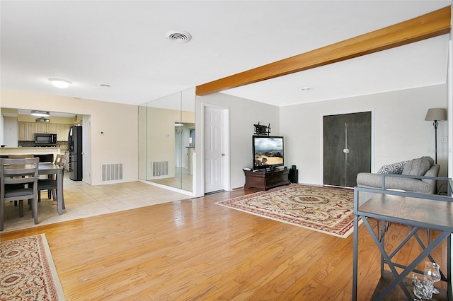 living room featuring beamed ceiling and light wood-type flooring