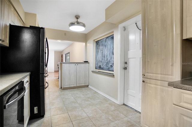 kitchen featuring black fridge, light tile patterned floors, and stainless steel dishwasher