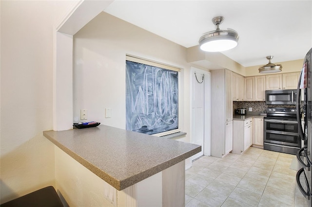 kitchen featuring cream cabinets, decorative backsplash, light tile patterned floors, kitchen peninsula, and stainless steel appliances