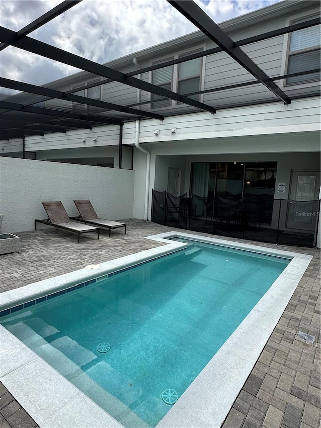 view of swimming pool featuring glass enclosure and a patio