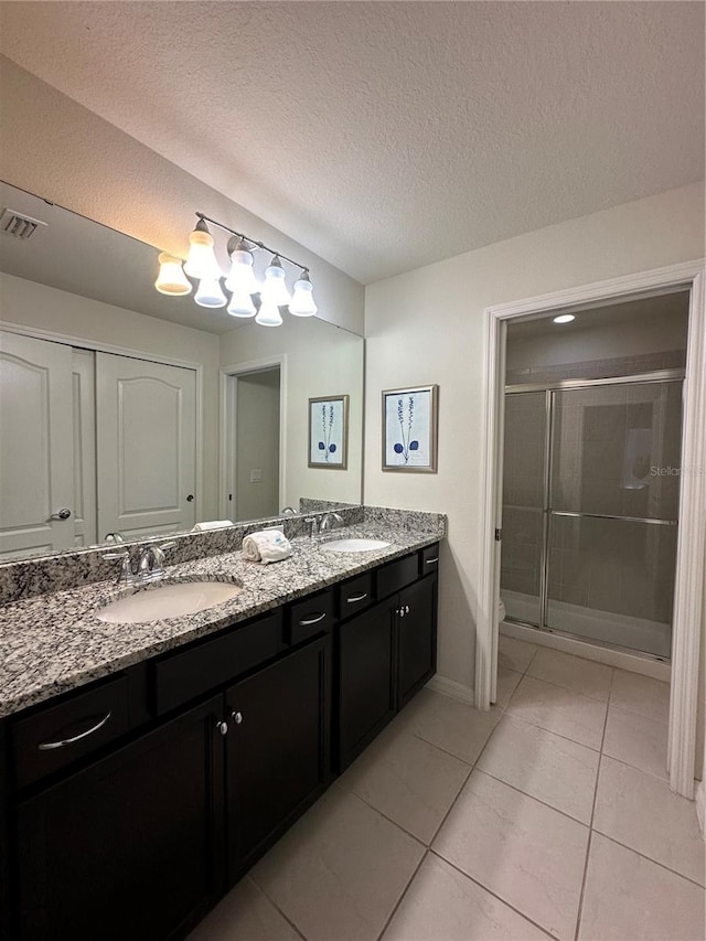 bathroom featuring tile patterned flooring, vanity, a textured ceiling, and a shower with door